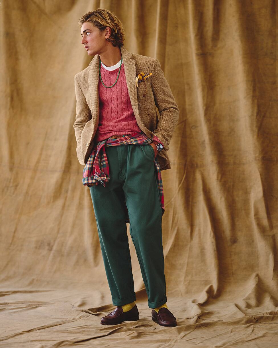 Homme portant un pull rouge, un blazer beige, un jean et des mocassins.