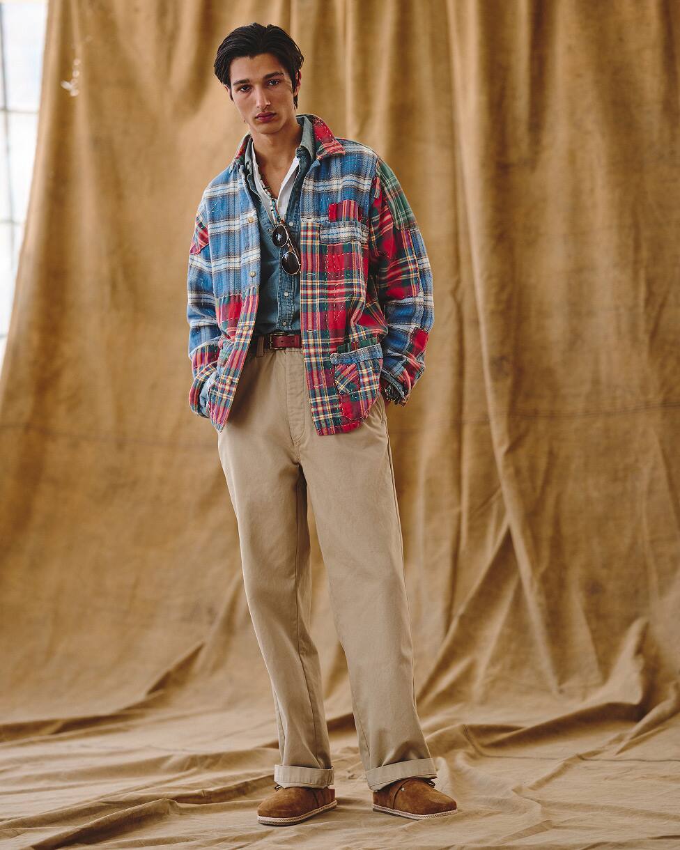 Homme portant une chemise en flanelle glissée sur une chemise en denim, avec un pantalon beige et des mocassins.